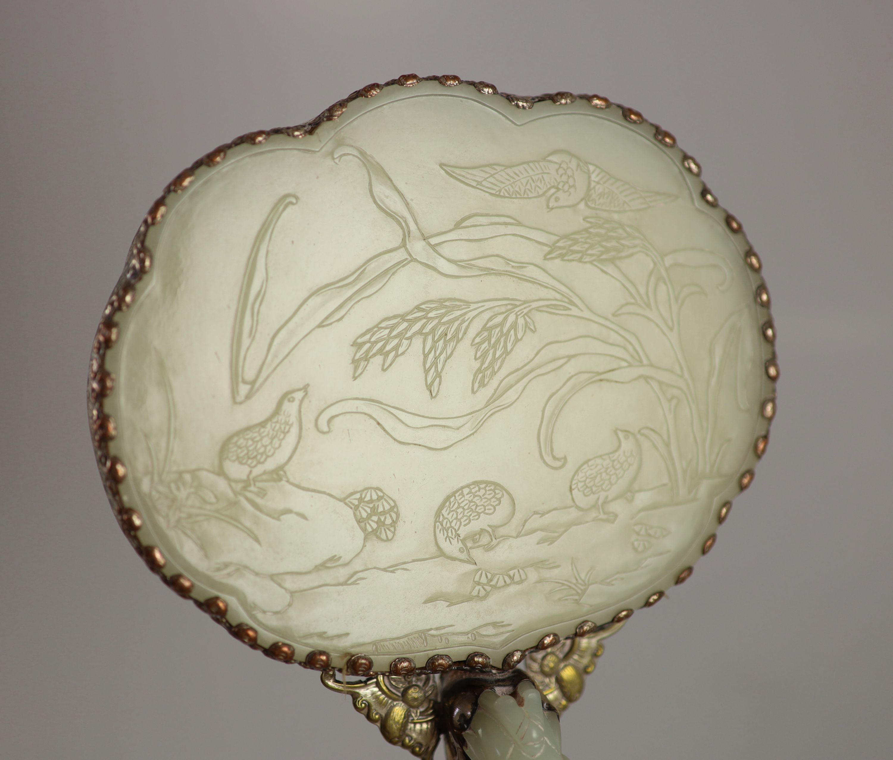 A Chinese pale celadon jade mounted hand mirror, the jade 18th/19th century, 24.2cm long, plaque 13.2 x 11.5cm, belt hook handle 12.3cm